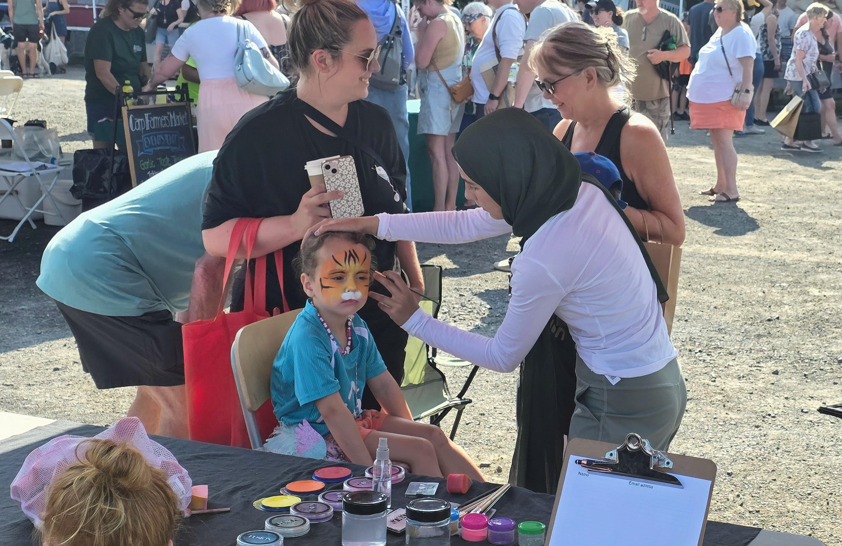 Maryam Fitzgerald painting a child's face at the Carp Farmers Market, Ottawa